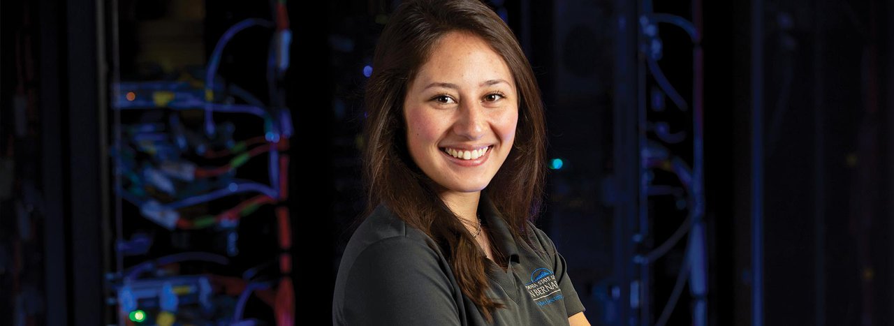 Female cybersecurity student smiling inside computer server room