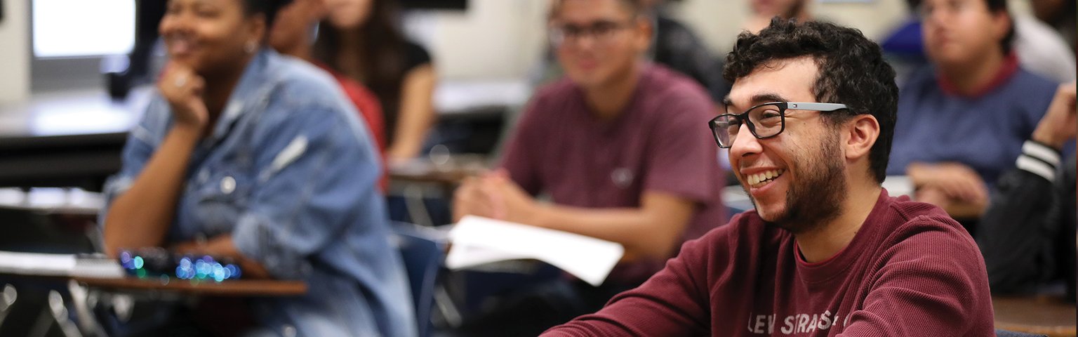 Student smiling while sitting at a desk