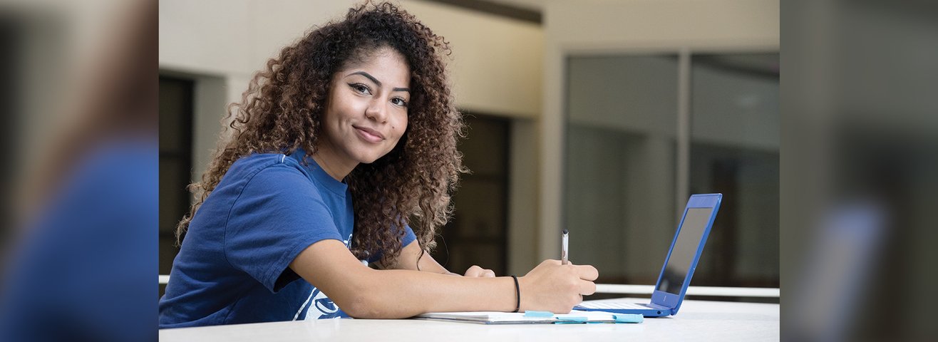 CSUSB student studies with laptop and note pad. 