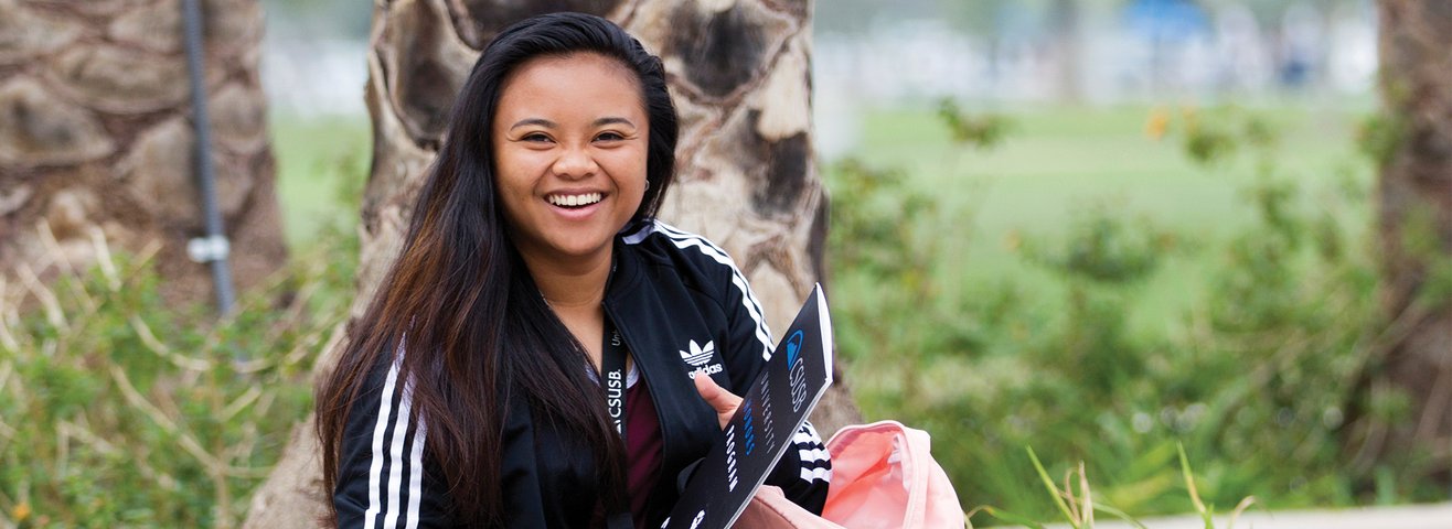 Student smiles while sitting on bench. 